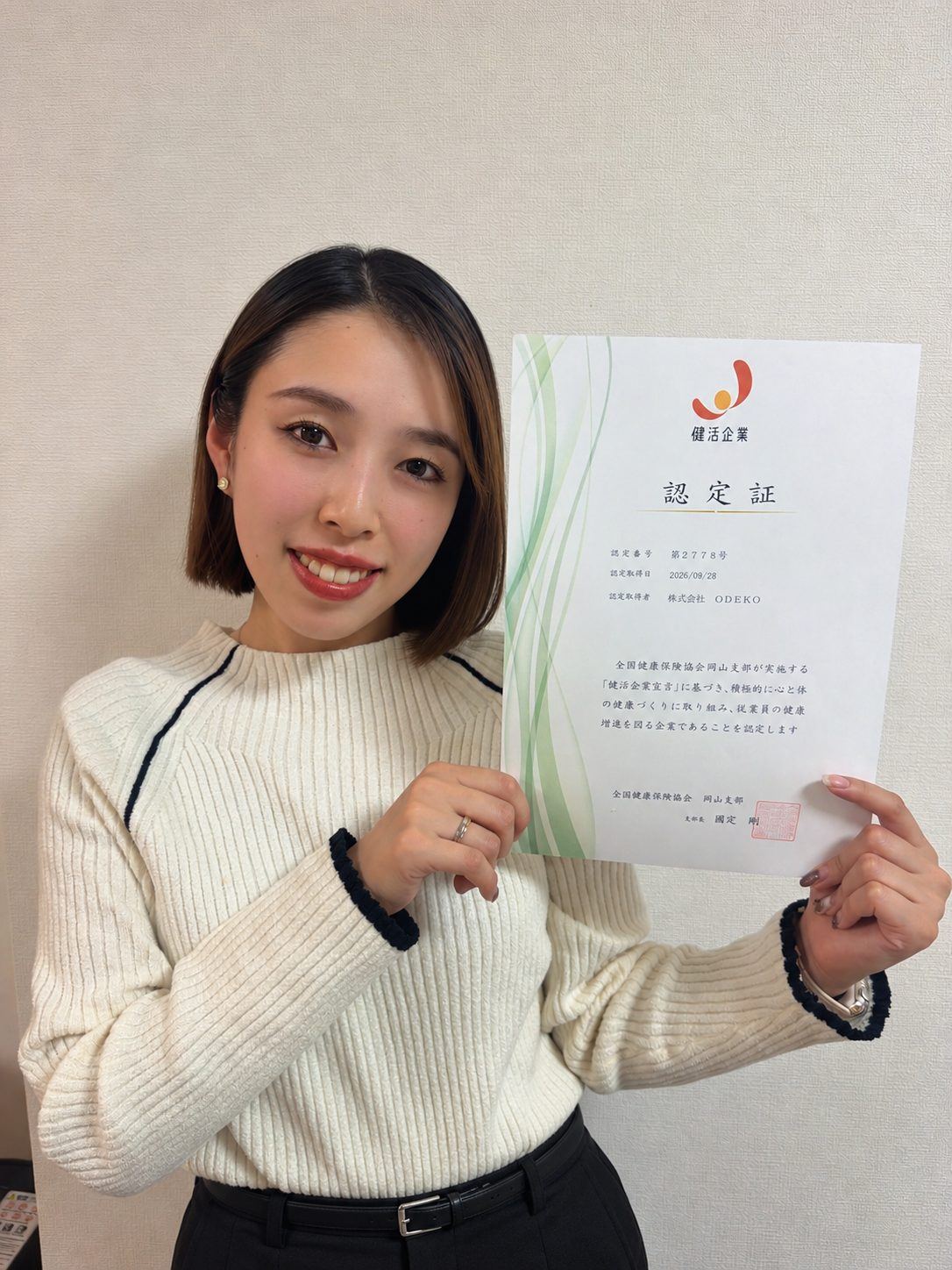 健活企業の認定証を持つODEKOのスタッフ